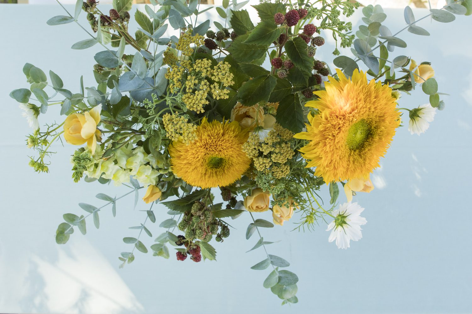 A bouquet of sunflowers and greenery on a table.