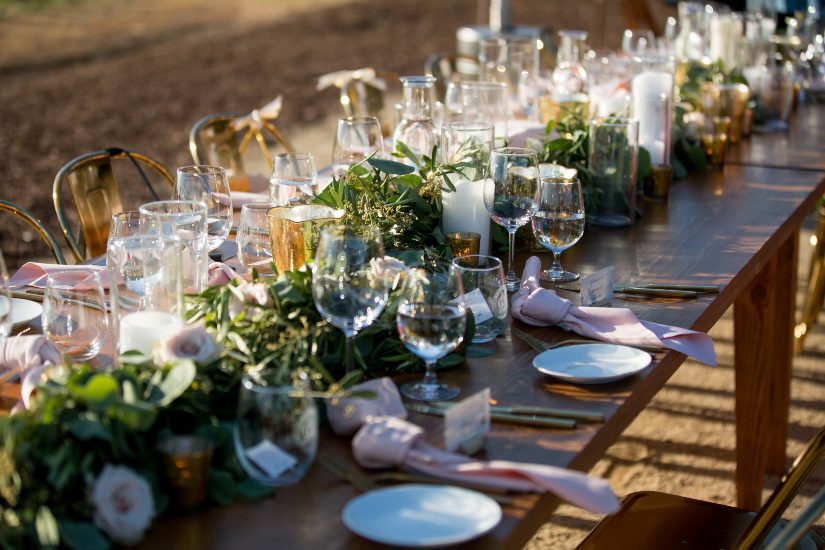 A long table set with greenery and gold plates.