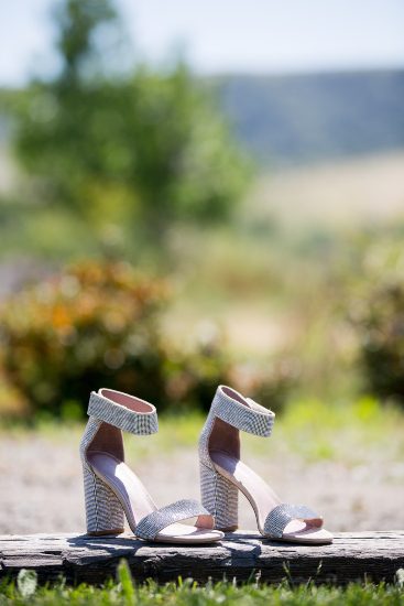 A pair of white wedding shoes sitting on a wooden bench.