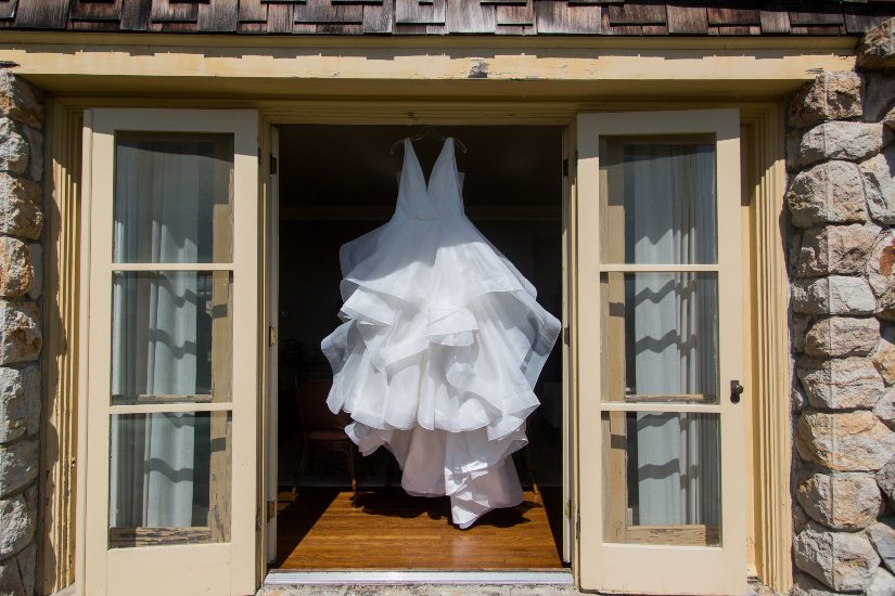 A wedding dress hangs from the door of a house.