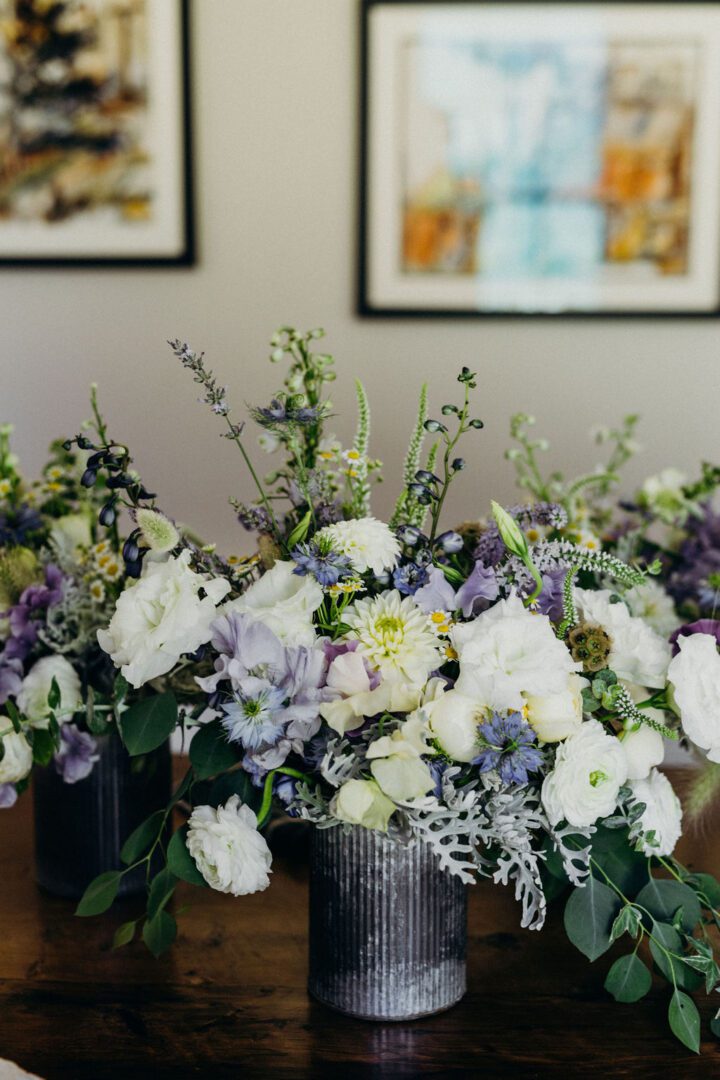 A white and purple floral arrangement on a wooden table.