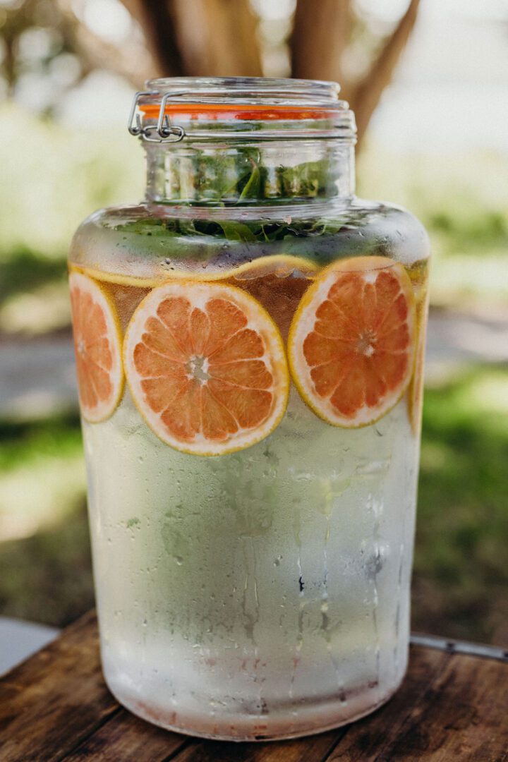 A jar of water with orange slices in it.