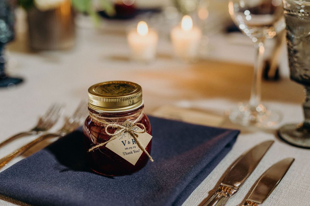 A jar of jam sits on a table setting.