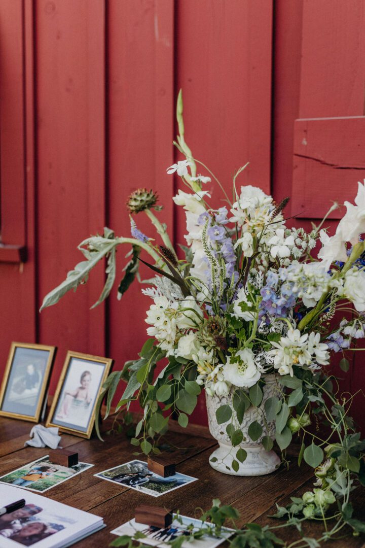 A vase of flowers on a table next to a red wall.