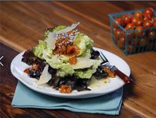 A plate of salad with tomatoes and lettuce on a wooden table.