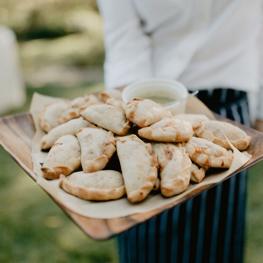 A man is holding a tray of empanadas.