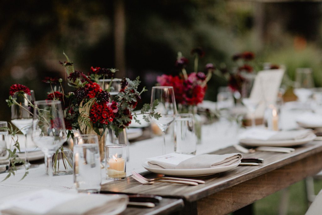 A long table set with red and white flowers.