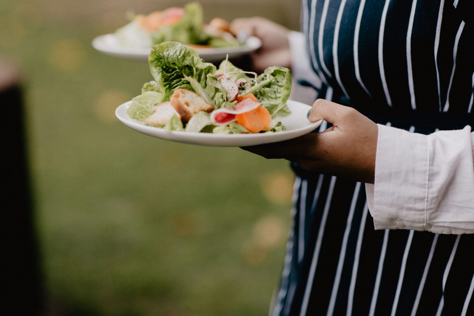 A woman is holding a plate of salad.