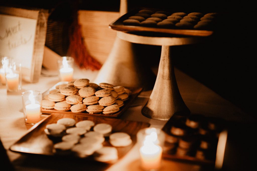Macarons and cookies on a table with candles.