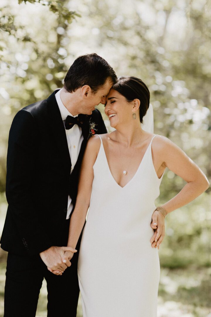 A bride and groom embracing in the woods.