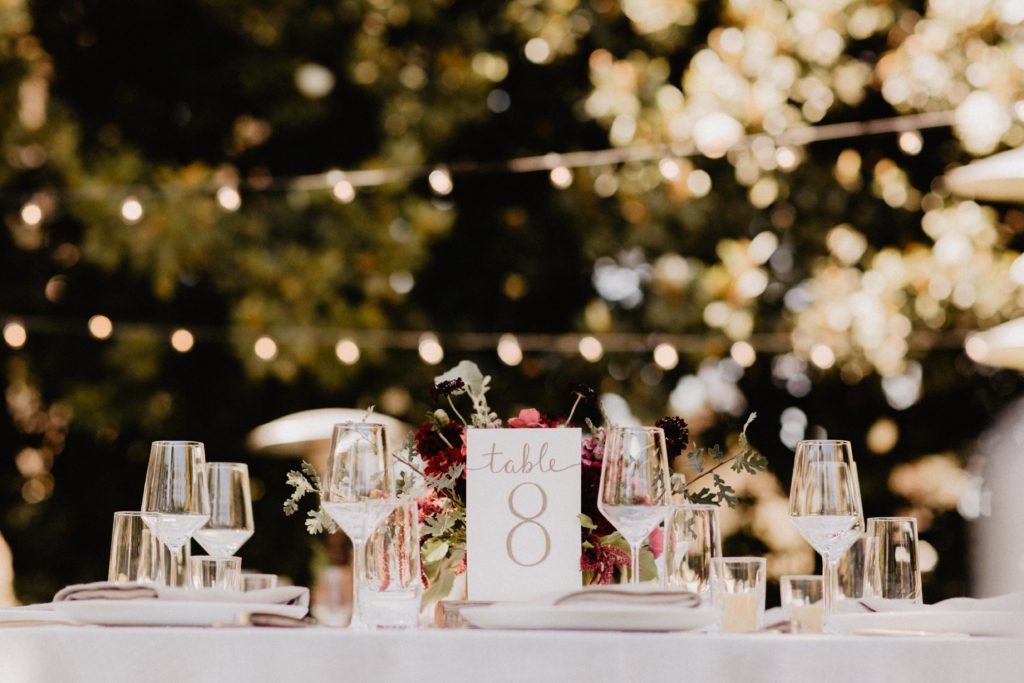 A table setting with wine glasses and a string of lights.