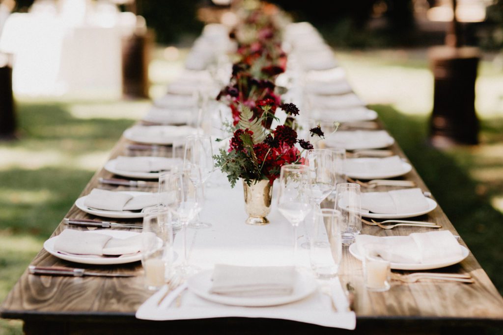 A long table set with place settings and flowers.