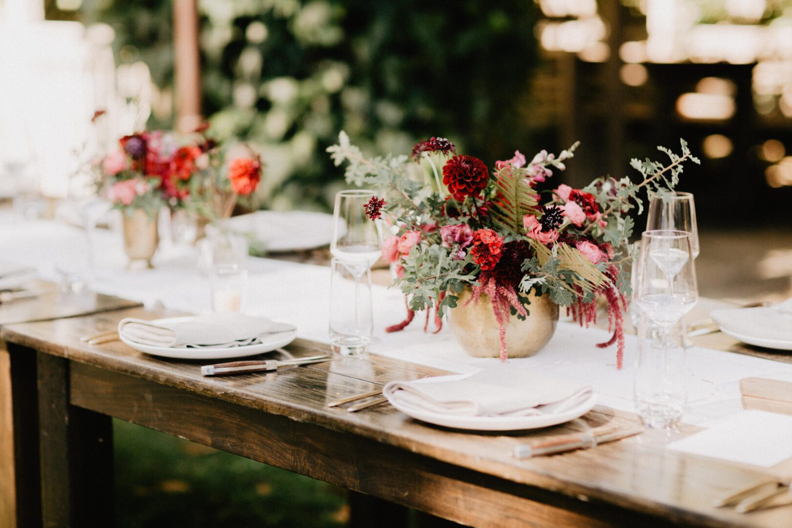 A wooden table with flowers and plates on it.