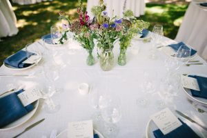 A table setting with blue napkins and flowers.
