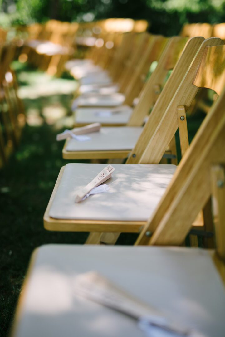 A row of wooden chairs at an outdoor wedding.