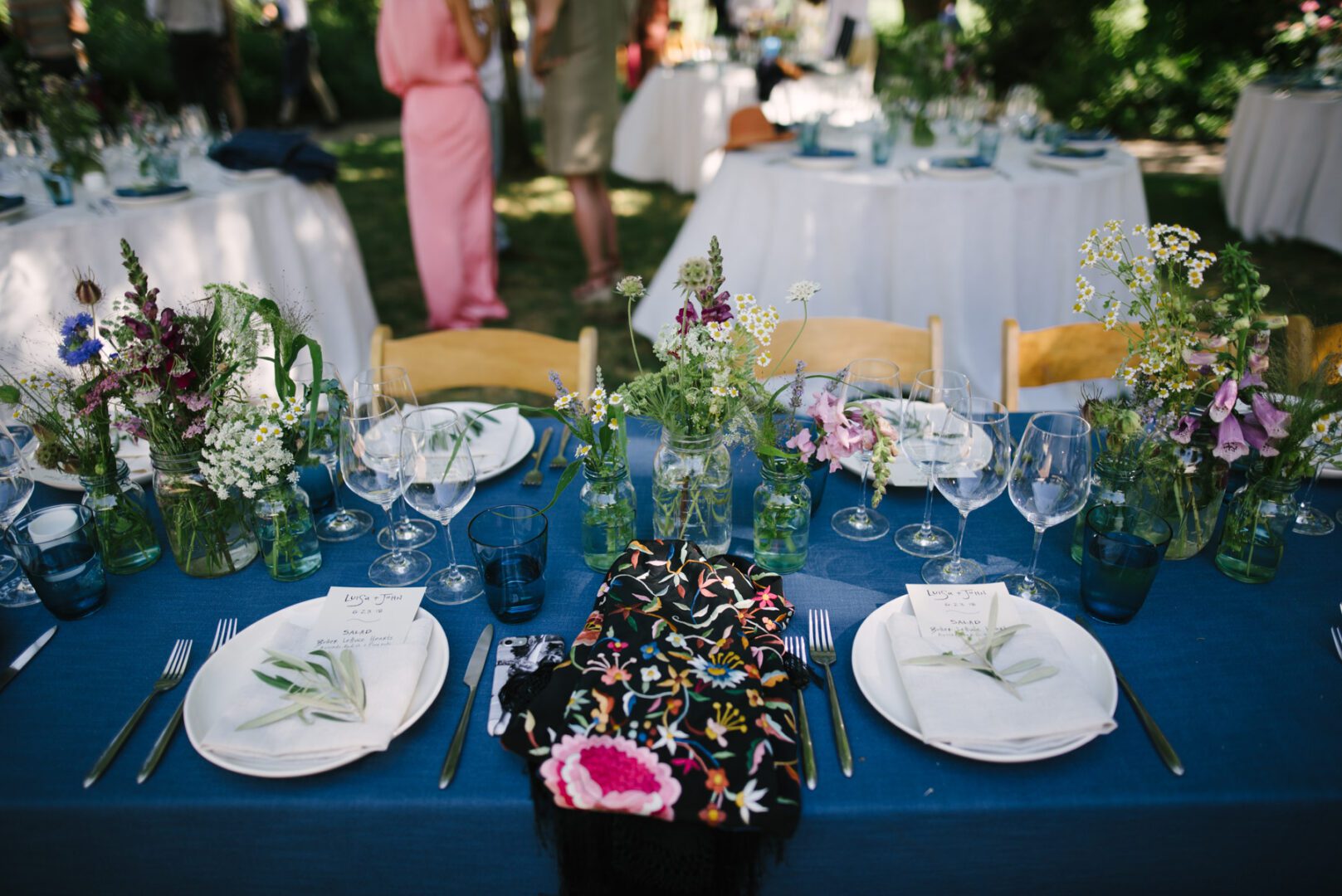 A blue tablecloth with flowers and plates on it.