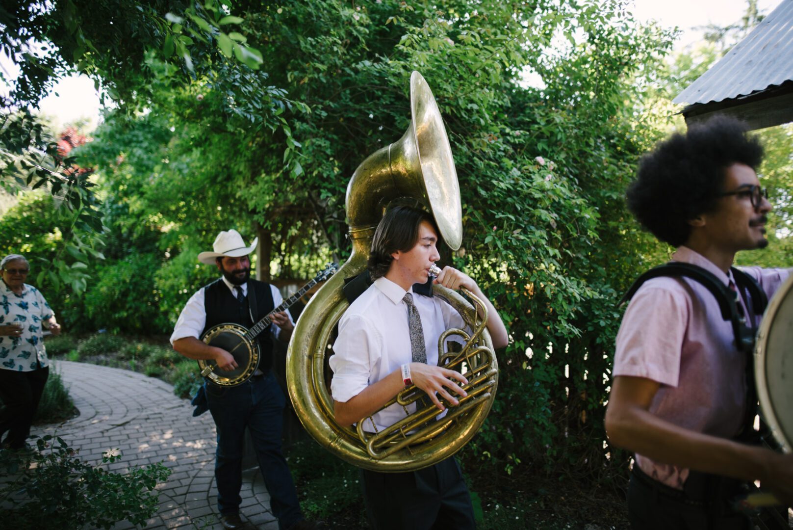 A group of men playing a tuba in a garden.