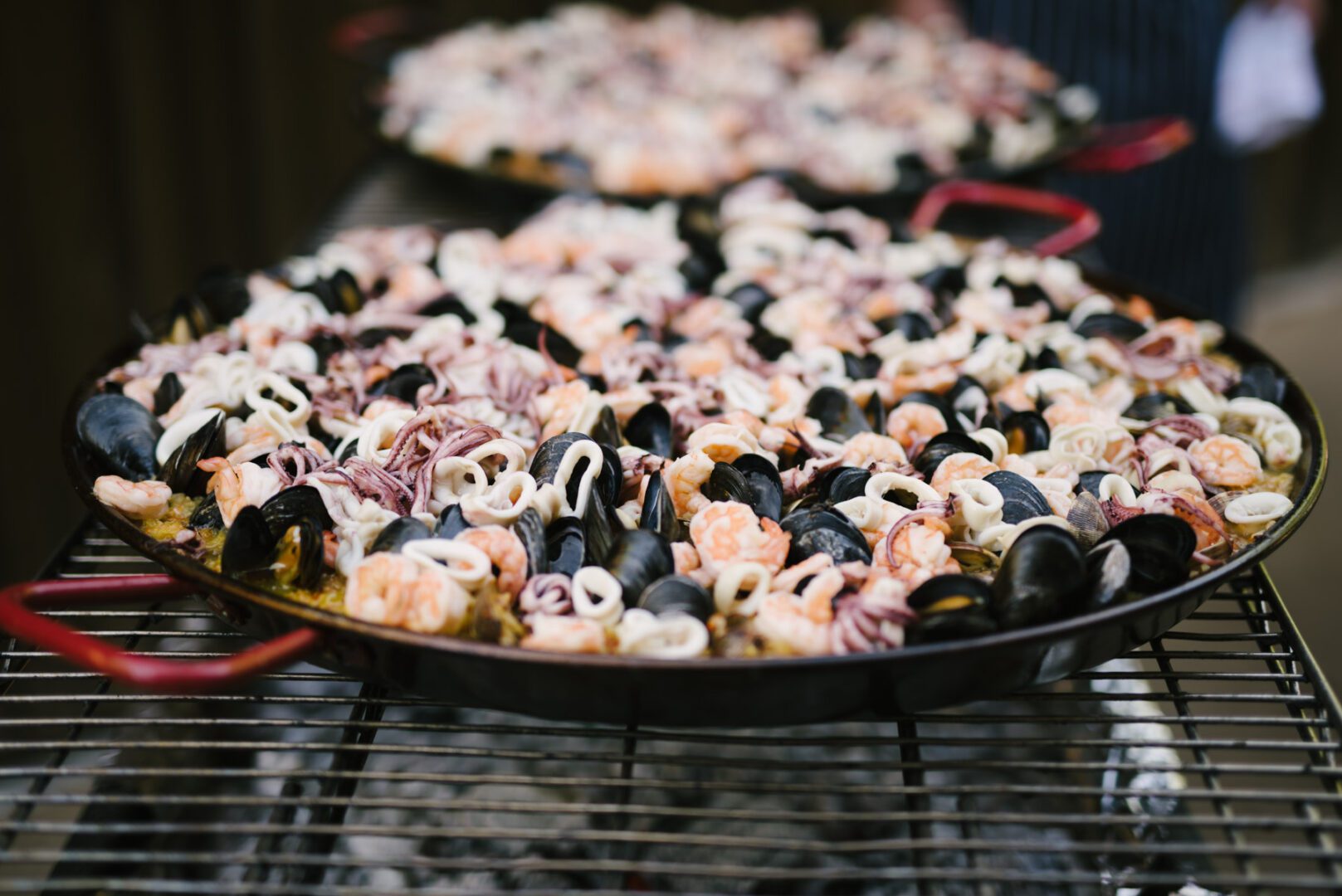 A pan full of seafood and clams on a grill.