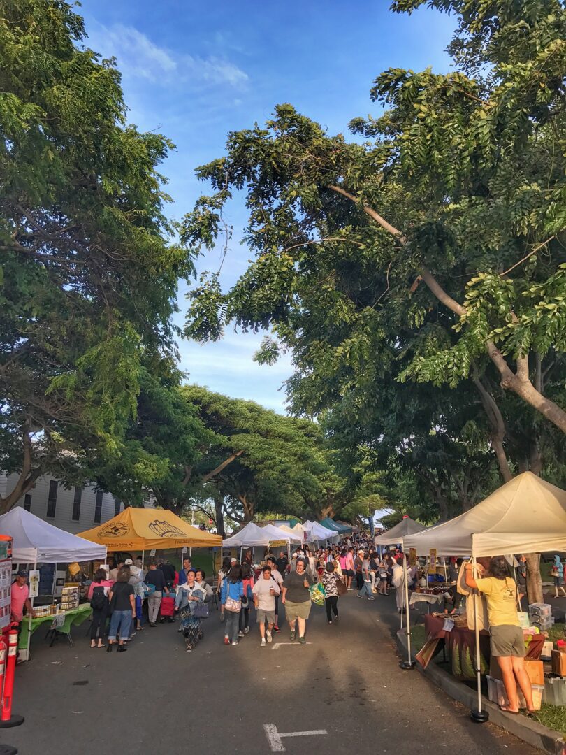 A street full of people and tents at a farmers' market.