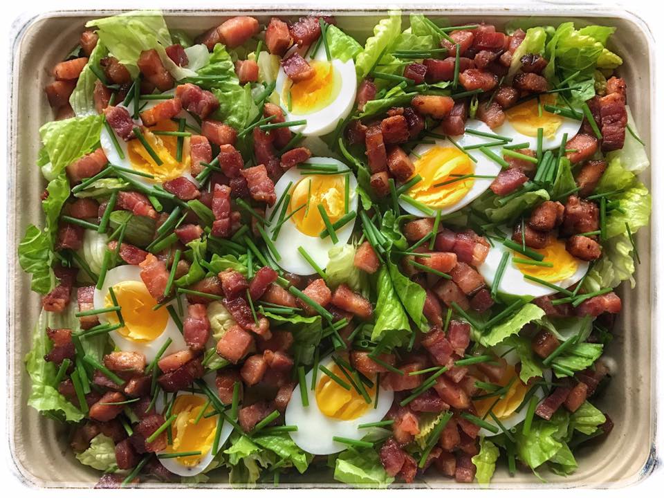 A salad with bacon, eggs and lettuce.