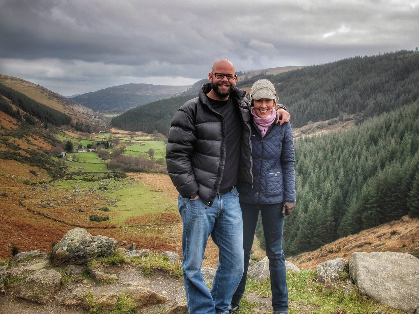 A man and woman standing on top of a hill in a valley.