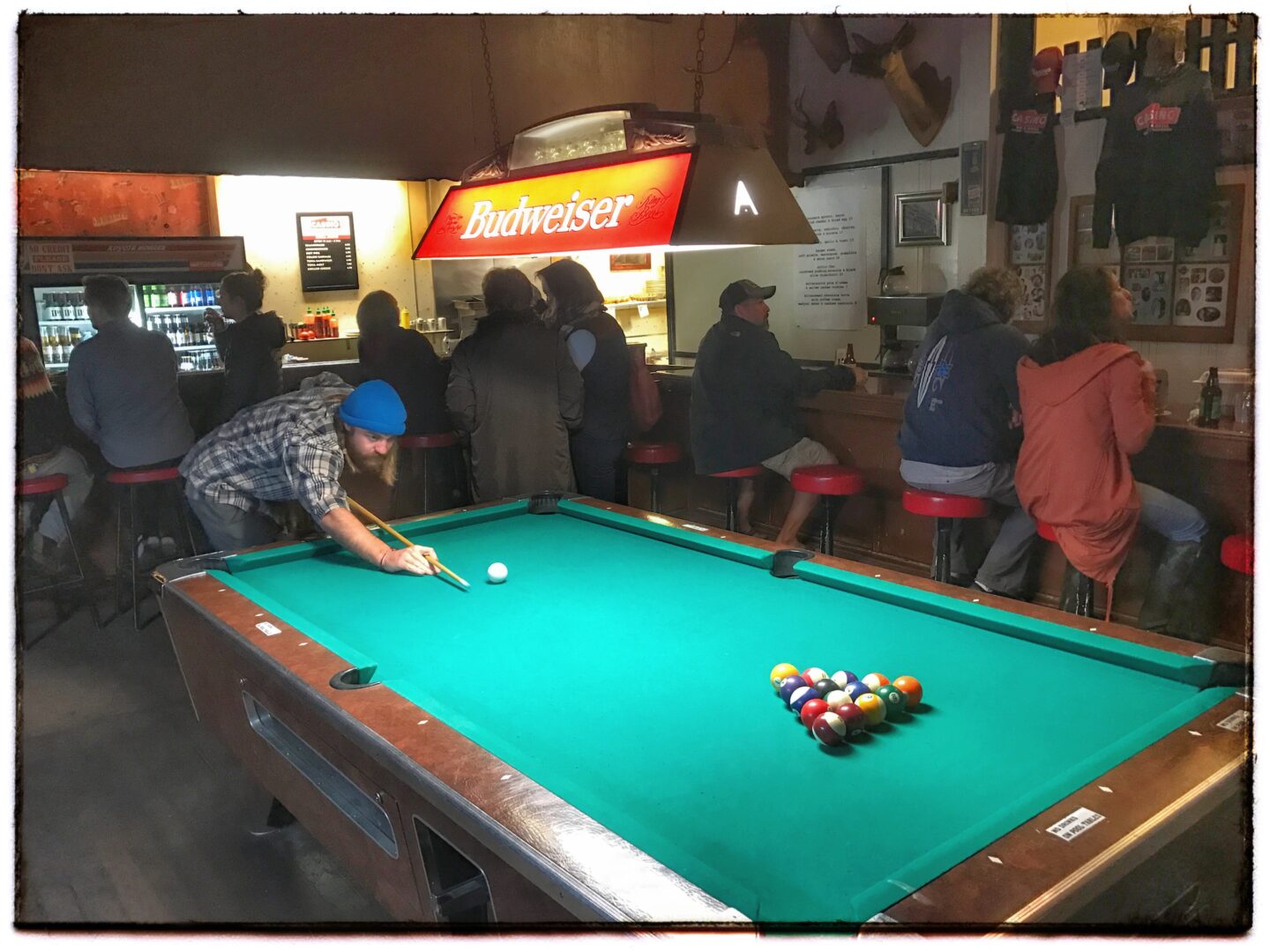 A group of people playing billiards in a bar.