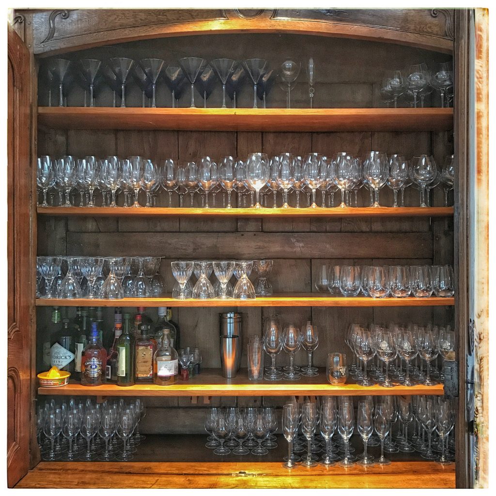 A wooden cabinet filled with wine glasses.