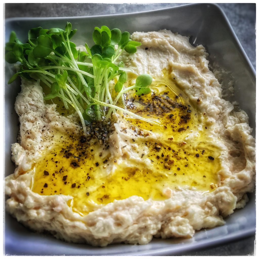 Hummus with olive oil and parsley on a plate.