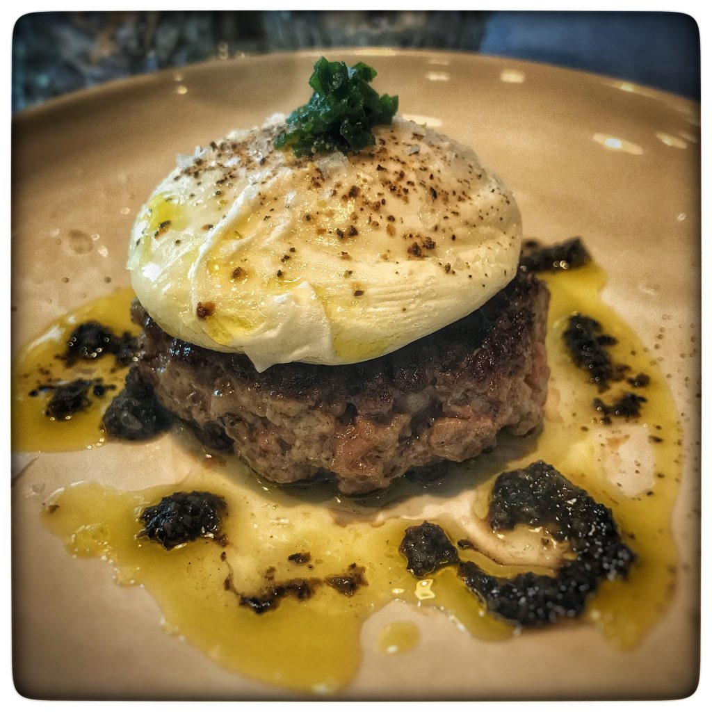 A plate with a burger and egg on top.