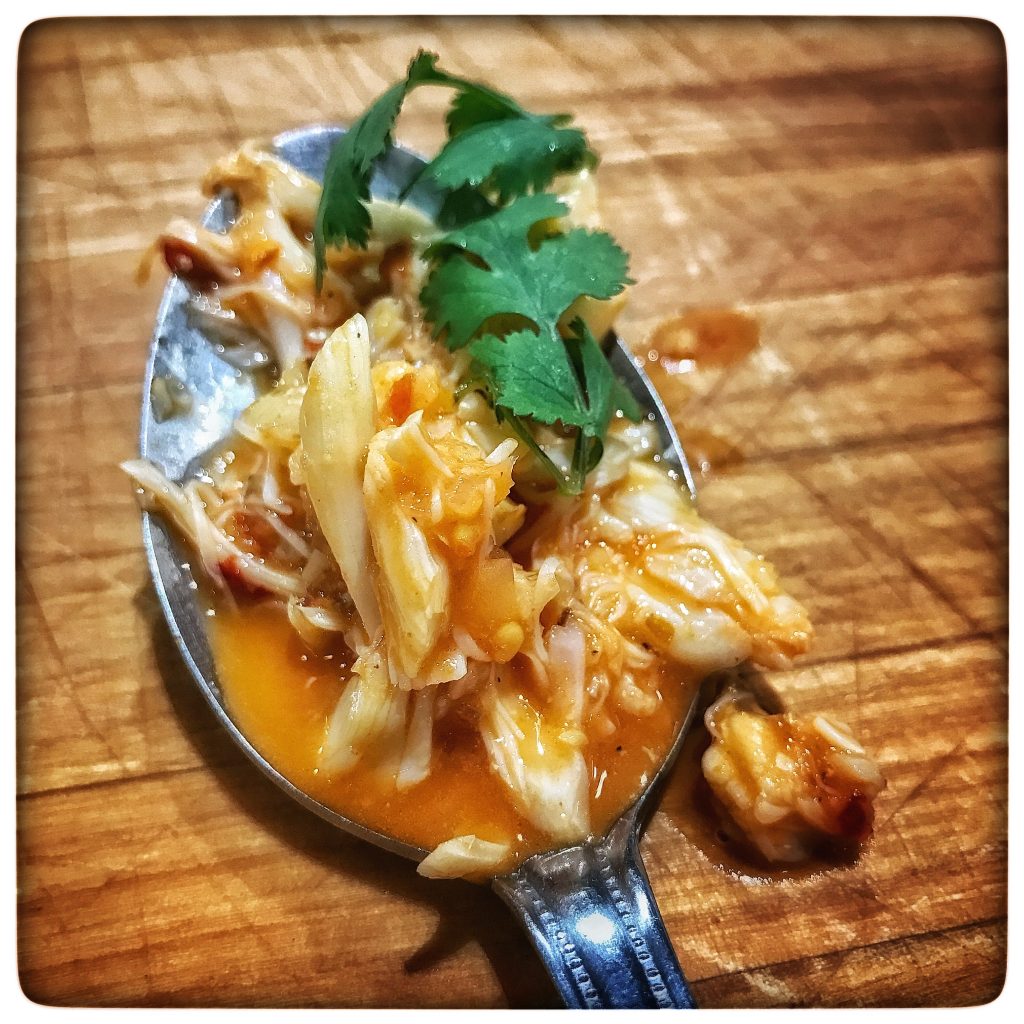 A spoon full of food on a wooden table.