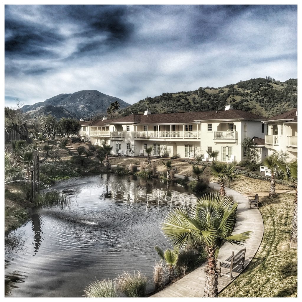 An apartment complex with a pond and mountains in the background.