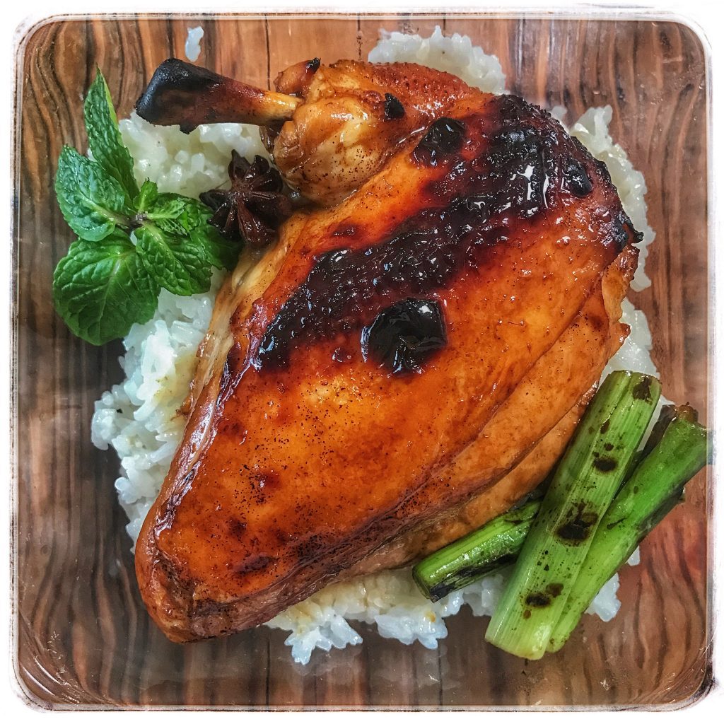 A chicken on a plate with rice and greens.