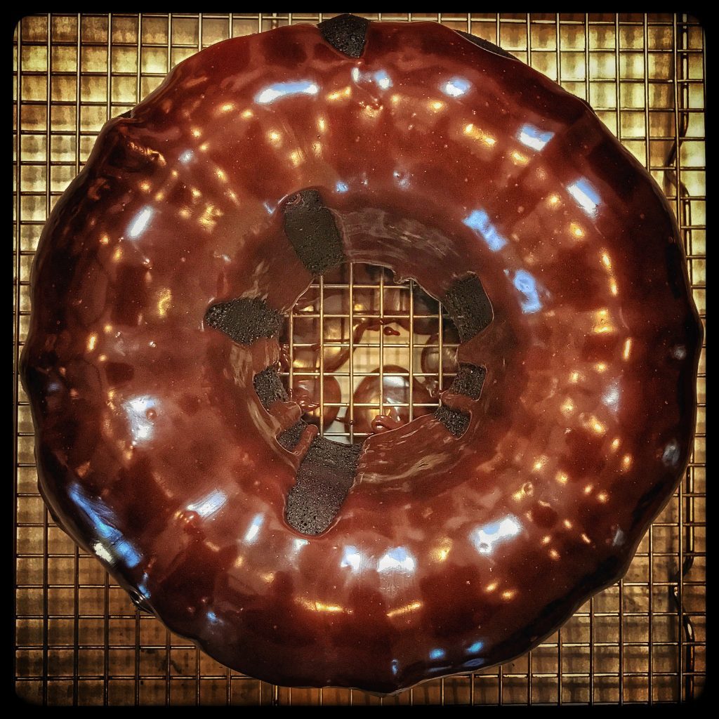 A chocolate donut on a cooling rack.