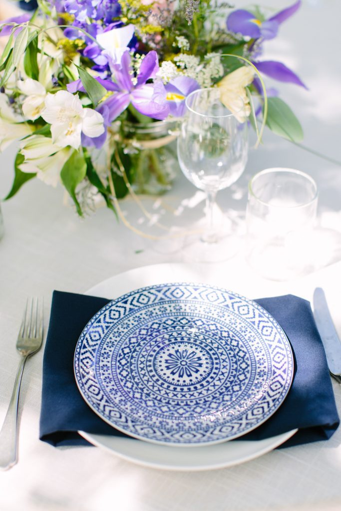 A table setting with a blue plate and purple flowers.