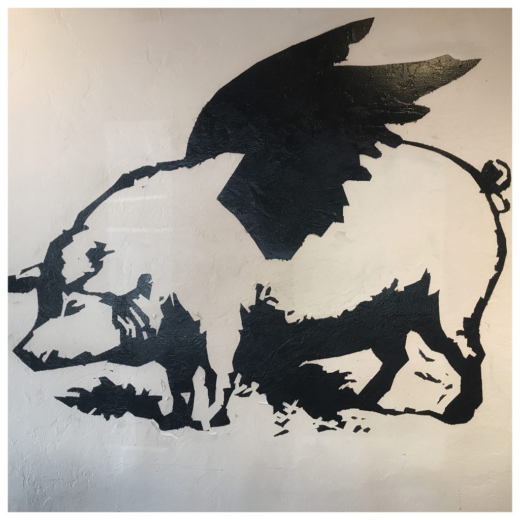 A black and white painting of a pig with wings.