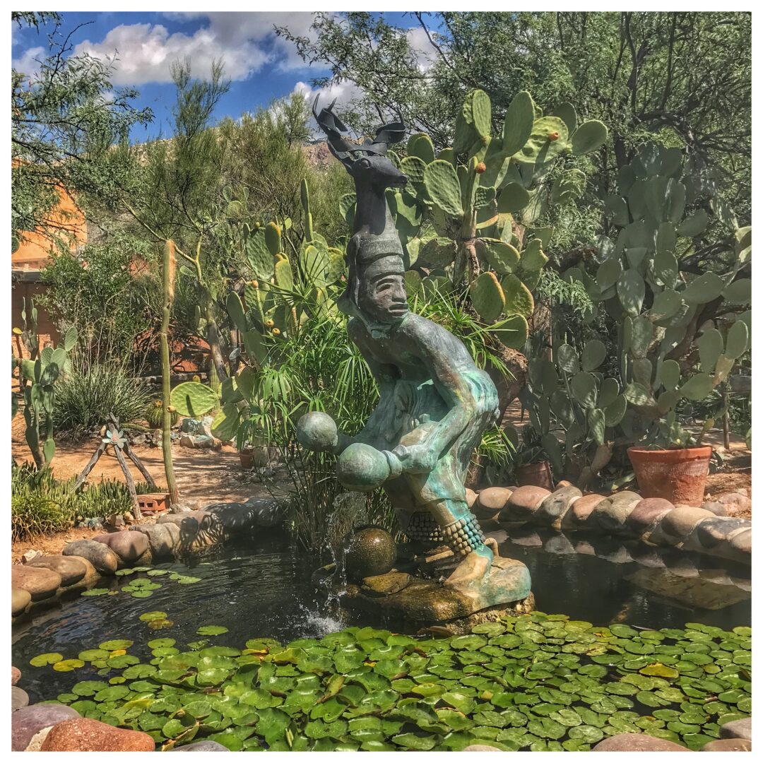 A statue of a man in a cactus garden.
