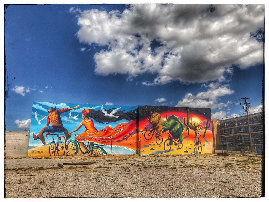 A mural of a woman riding a bike in the desert.