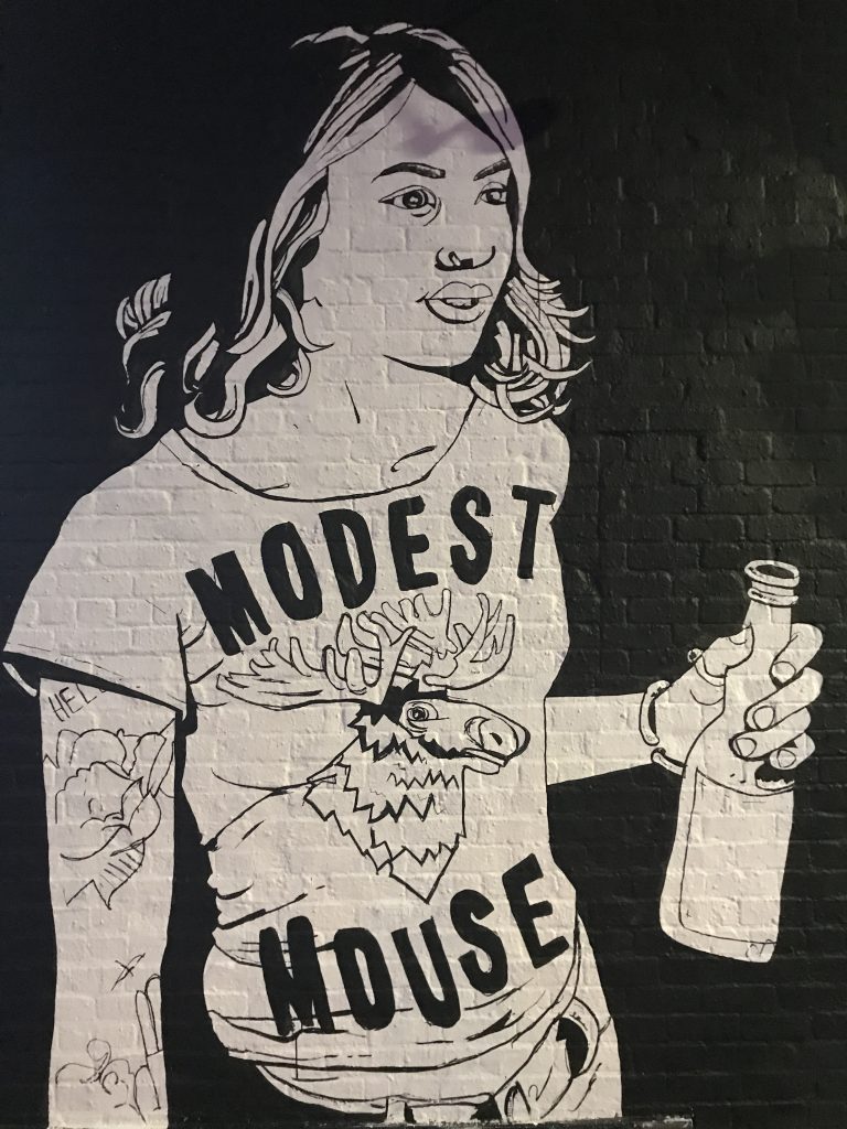 A black and white mural of a woman holding a bottle of beer.