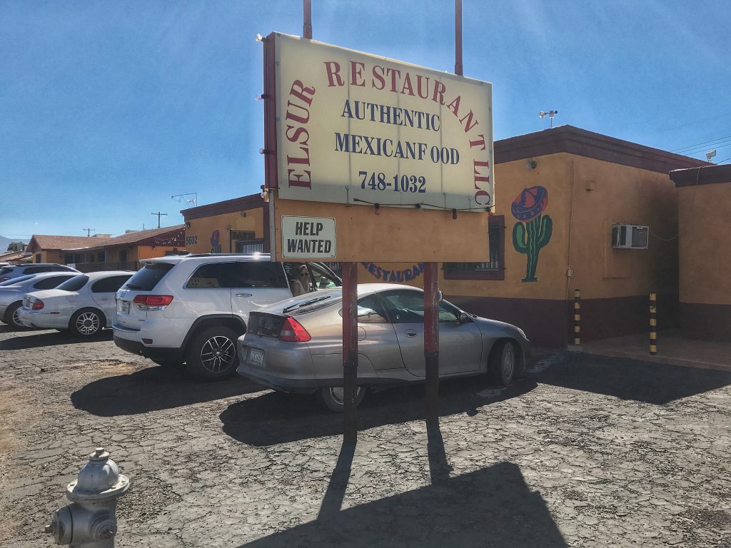 A mexican restaurant with cars parked in front of it.