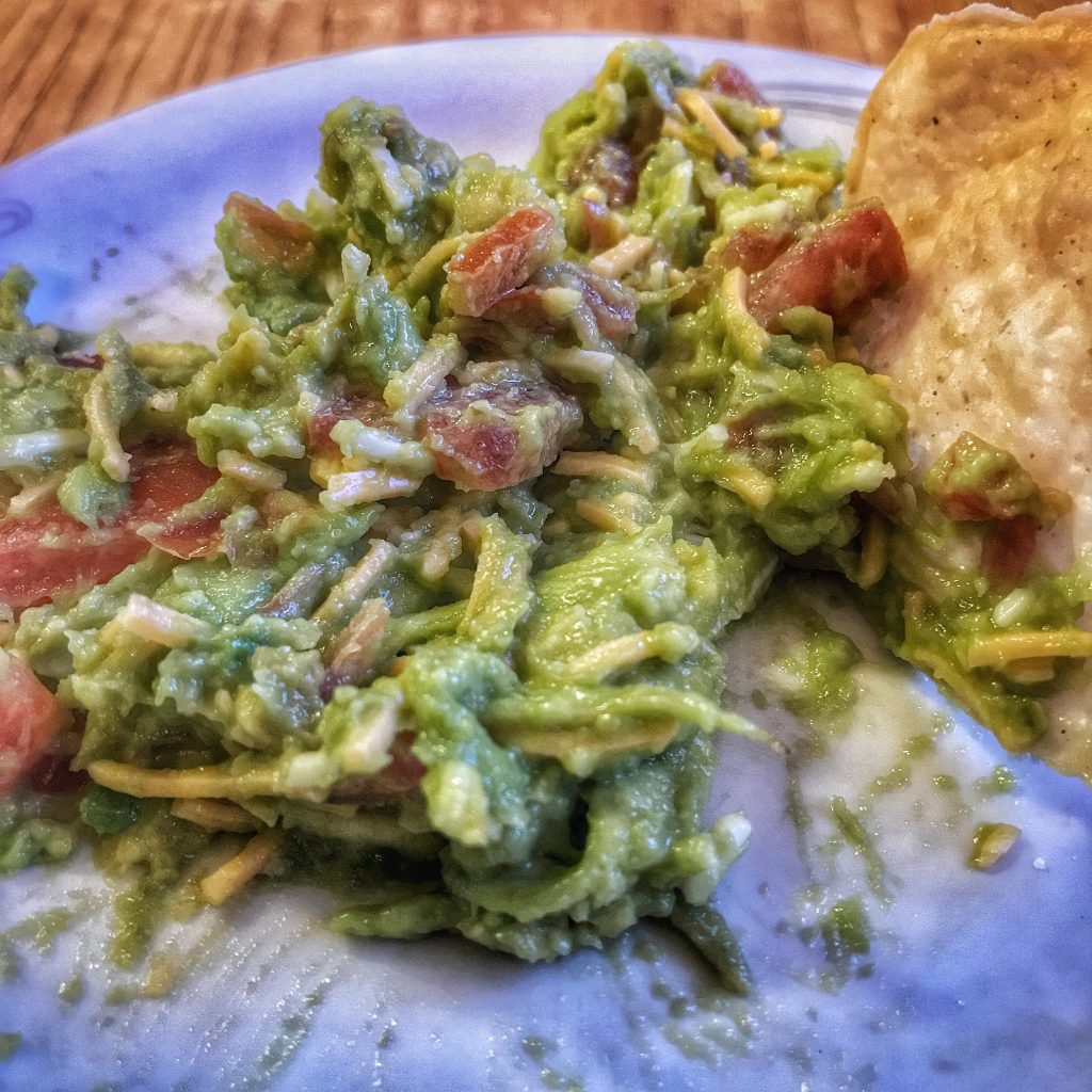 A plate with guacamole and a tortilla on it.