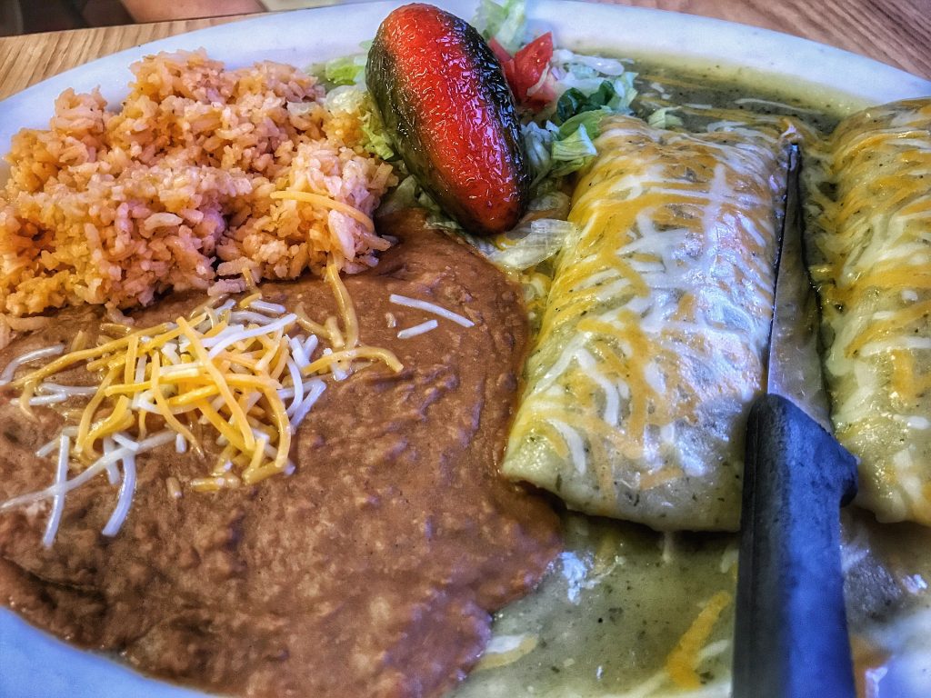 A plate with enchiladas, rice and beans.