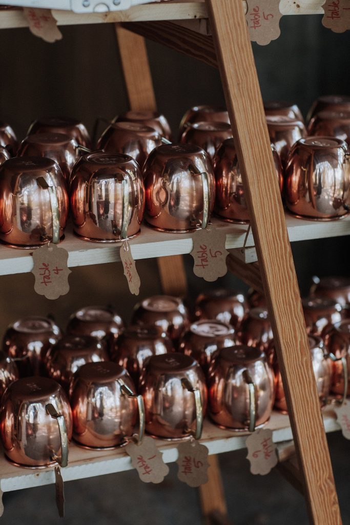 A row of copper mugs on a shelf.