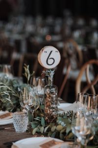 A table setting with greenery and a number on it.