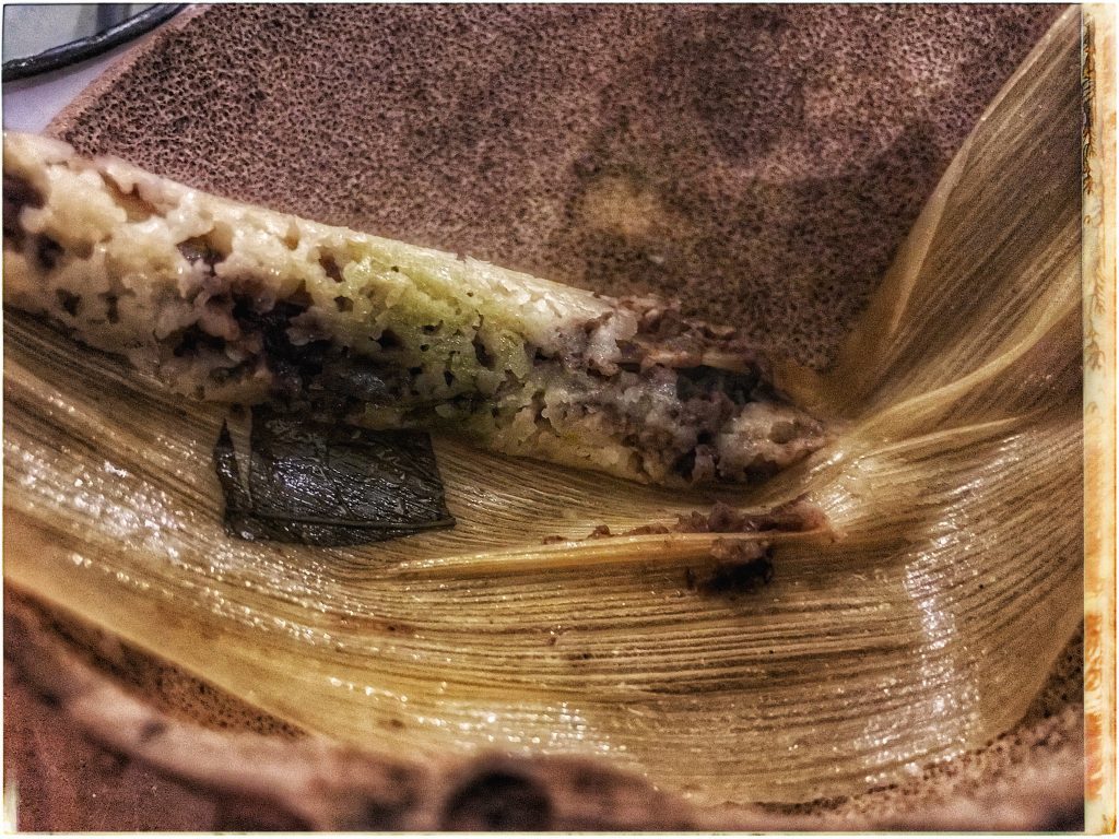 A close up of a tamale with a piece of meat in it.