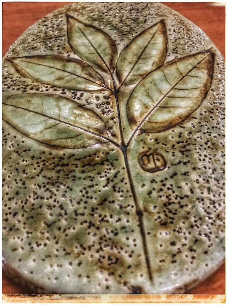 A ceramic plate with a leaf design on it.