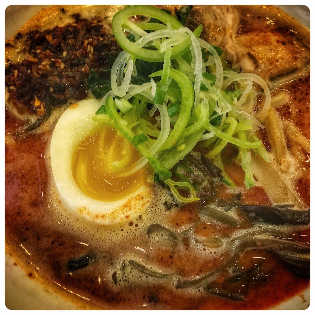 A bowl of ramen with an egg on top.