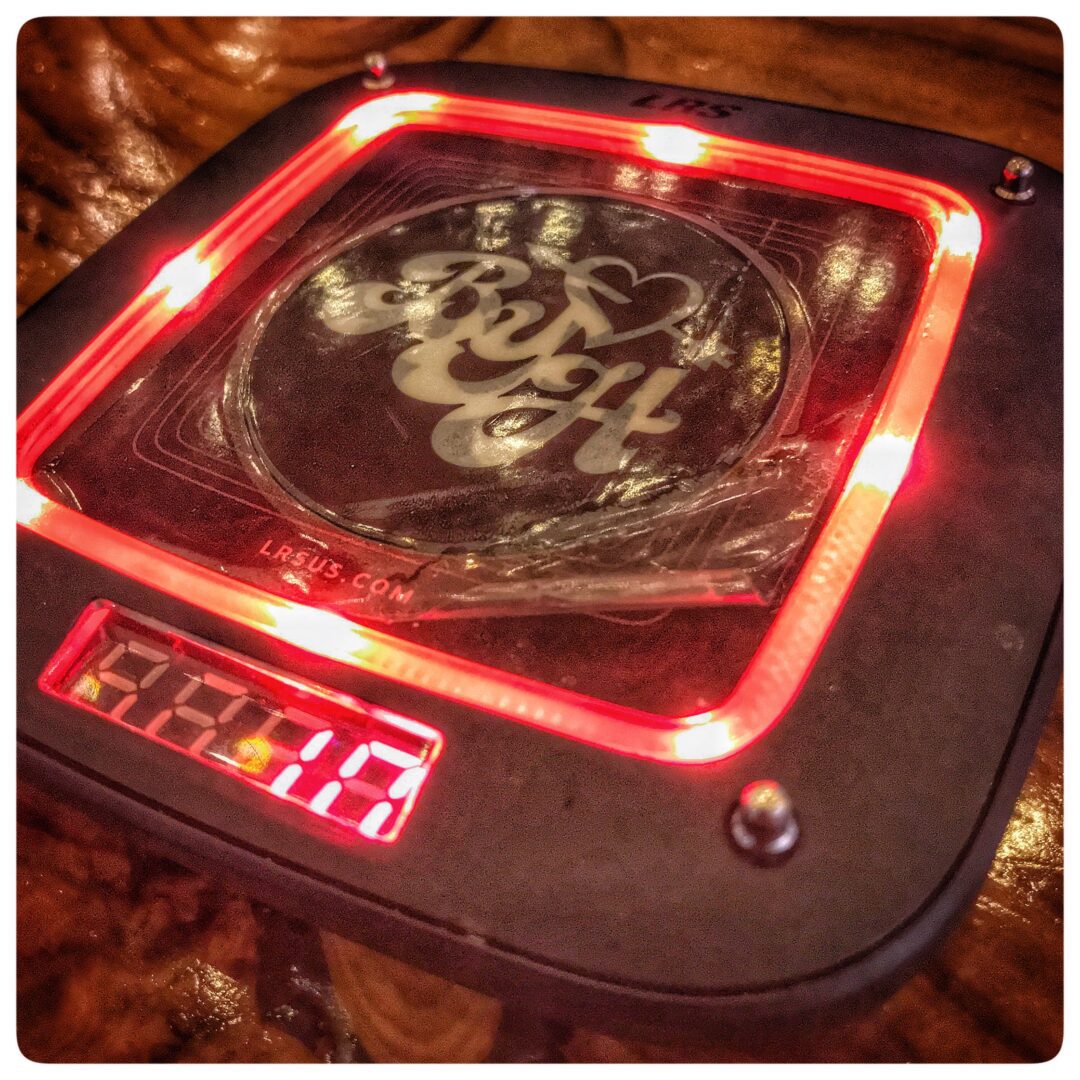 A clock on a table with a red light on it.