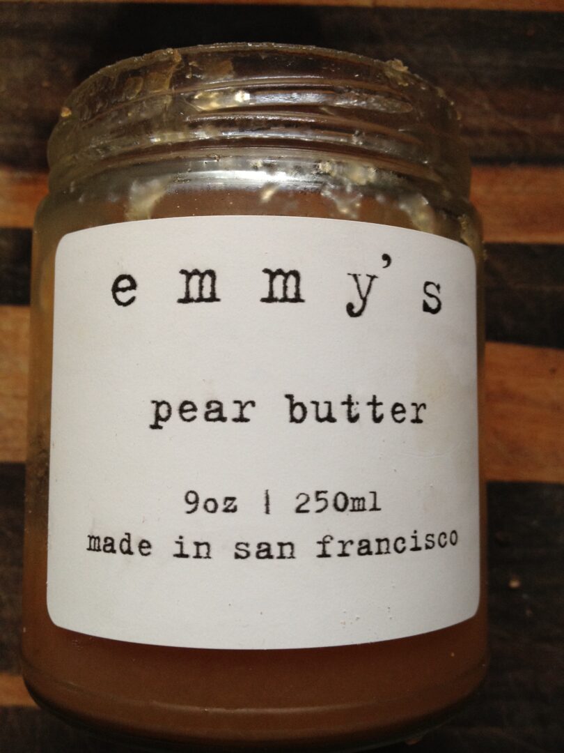 A jar of emmy's pear butter on a wooden table.