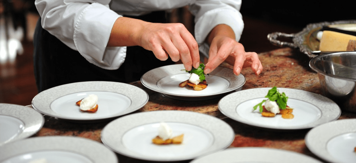 A chef preparing a plate of food on a table.