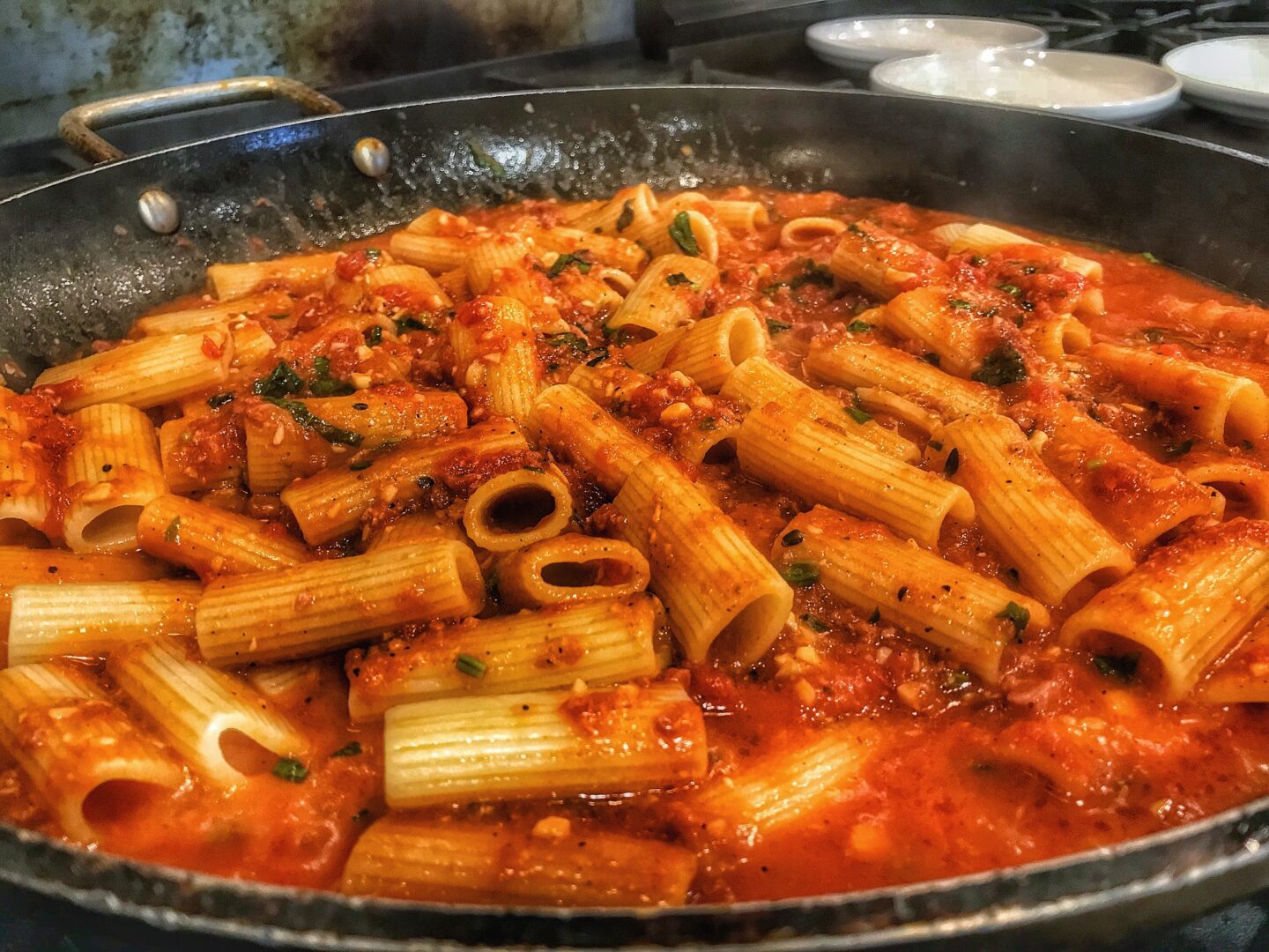 A pan full of pasta and sauce on a stove.